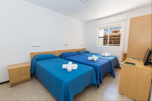 2 camas en una habitación con sábanas azules en Hostal El Mercat, en Villajoyosa