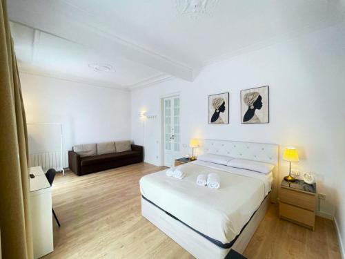 ein weißes Schlafzimmer mit einem Bett und einem Sofa in der Unterkunft Flor Habitaciones in Barcelona