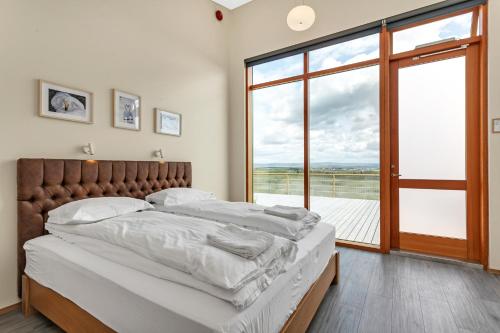 um quarto com uma cama grande e uma janela grande em 4bed 4bath Sauna & Hot tub em Reykholt
