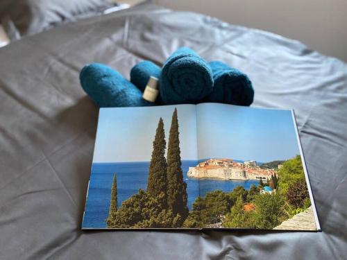 a book on a bed with a picture of the ocean at Clear Water Apartment - Sea and Sun in Mandre
