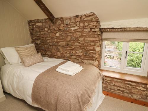 a bed in a room with a stone wall at Groveside in Hereford