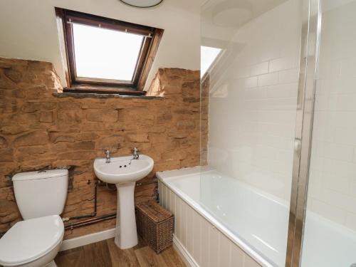 a bathroom with a toilet and a sink and a bath tub at Groveside in Hereford