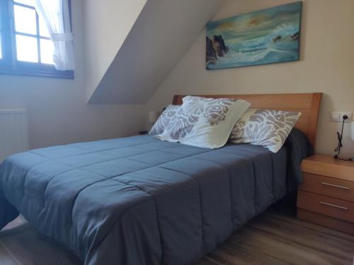 un letto con lenzuola blu e cuscini bianchi in una camera da letto di Casa da Escuela a Caldas de Reis