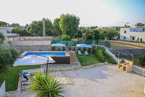 a backyard with a swimming pool and a patio with umbrellas at B&B Trulli Donna Isabella in Locorotondo
