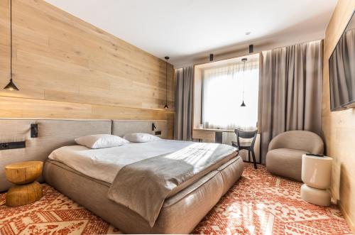 Hotel Wisła Premium في فيسلا: غرفة نوم بسرير كبير وكرسي