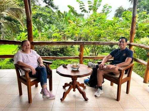 a man and woman sitting at a table on a porch at Natura Gardens Galápagos in Bellavista