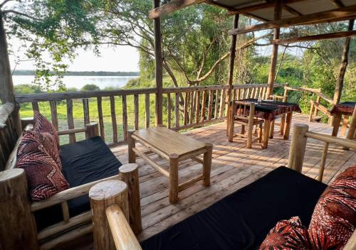 a wooden deck with chairs and tables on it at Murchison Giraffe Camp in Murchison Falls National Park