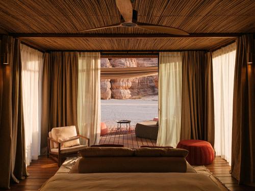 a bedroom with a bed and a couch and a window at Our Habitas AlUla in AlUla