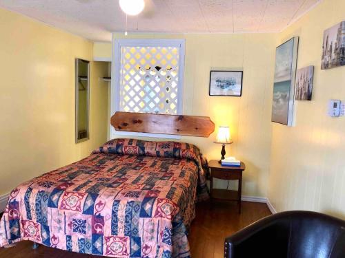 a bedroom with a bed and a chair and a window at Lakelawn B&B and Motel in Yarmouth