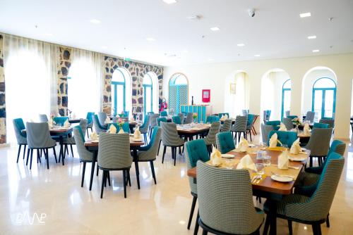 un comedor con mesas, sillas y ventanas en Dibba Mountain Park Resort, en Fujairah