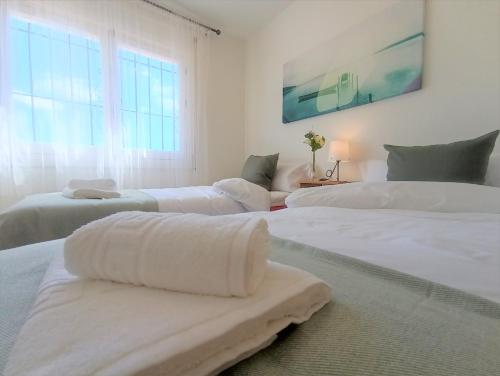 Villa del Sol في بينالمادينا: غرفة نوم بيضاء بثلاث اسرة عليها مناشف