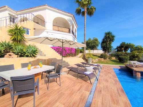 un patio con mesa, sillas y piscina en Villa del Sol, en Benalmádena