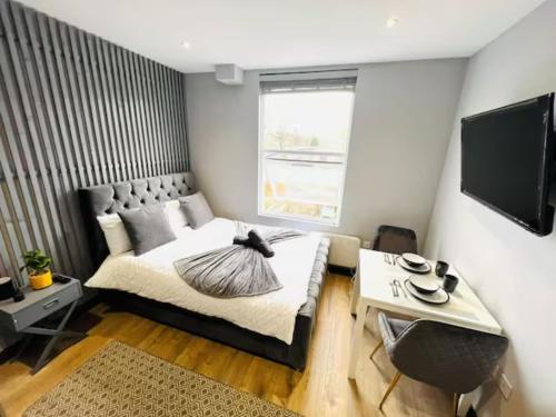 a bedroom with a bed and a table and a tv at Studios next to Emirates Stadium in London
