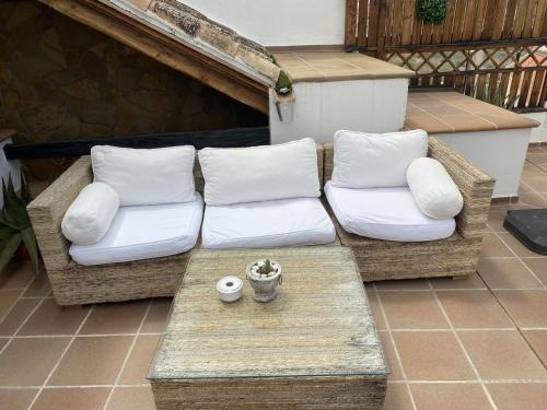 a wicker couch with white pillows on a patio at Alhanda Apartahotel in Benamaurel