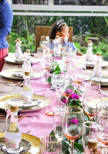 a table with wine glasses and a little girl sitting at it at Hospedaje Villa Eucalyptus in Nobsa