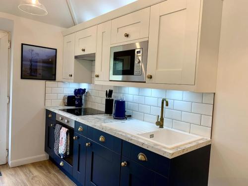 a kitchen with blue cabinets and a sink at Delightful 1 bed, 1 bath Norfolk Broads Guesthouse in Halvergate