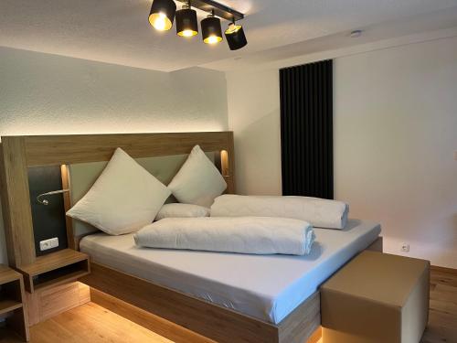1 dormitorio con 1 cama con sábanas y almohadas blancas en Ferienwohnungen Fellhornblick en Riezlern