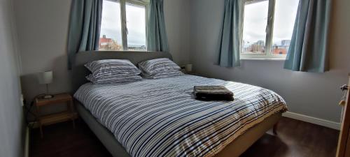 1 cama en un dormitorio con 2 ventanas en ExCel Exhibition Center Apartment en Londres