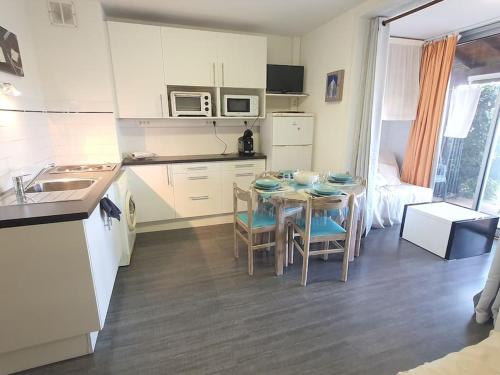 une cuisine avec une table et des chaises dans une pièce dans l'établissement Charmant T1 Barcarès Soleil Bleu, au Barcarès