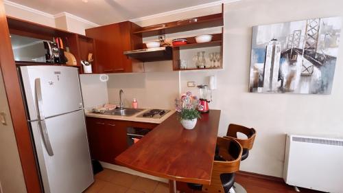 uma cozinha com uma mesa de madeira e um frigorífico em Apartamentos Bulnes em Santiago