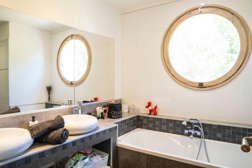 a bathroom with a tub and a sink and a mirror at Villa Aprile in Saint-Étienne-du-Grès