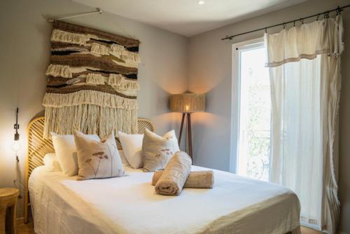 una camera da letto con un grande letto bianco con una finestra di Villa Aprile a Saint-Étienne-du-Grès