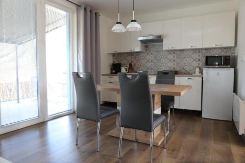 a kitchen with a wooden table and chairs in a kitchen at Apartmány Betica in Nesvady
