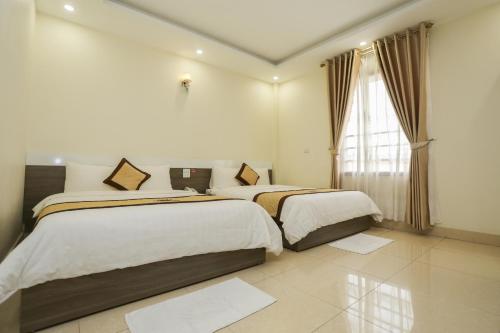 two beds in a hotel room with a window at Hotel Sunny HG in Ha Long