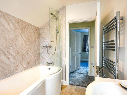 a bathroom with a tub and a shower and a sink at Pickle Cottage in Church Stretton