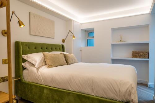 a bed with a green headboard in a room at Luxe Contemporary Cotswold Pad - Heart of Stow in Stow on the Wold
