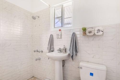 a white bathroom with a sink and a toilet at Serenity 2-Bed Apartment in Port Antonio in Port Antonio