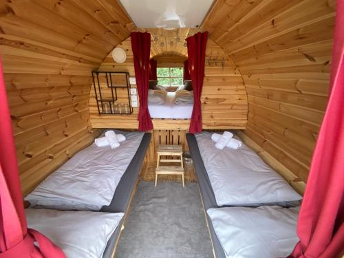 Habitación con 2 camas en una cabaña con cortinas rojas en Andrella Auszeithof - Schlaferlebnis im Holzfass en Friedersbach