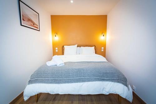 a bedroom with a large bed with an orange wall at L'Albatros 009 - Hypercentre * Cosy * Wifi in Saint-Quentin