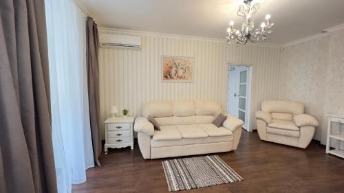 a living room with two chairs and a chandelier at Apartment in the Centre of City in Dnipro