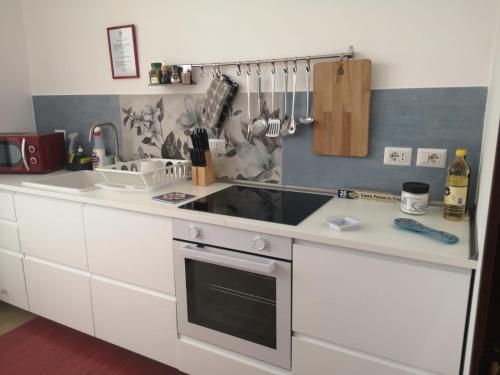 a white kitchen with a sink and a stove at Tulla's in Giardini Naxos