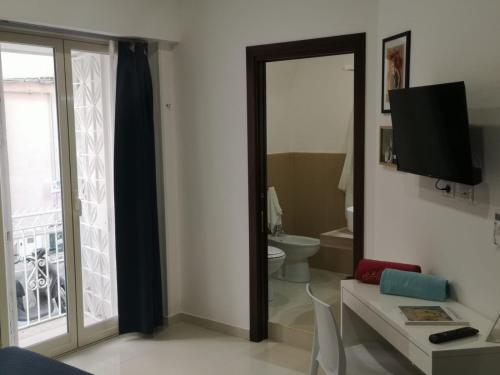 a bathroom with a toilet and a tv and a mirror at Tulla's in Giardini Naxos