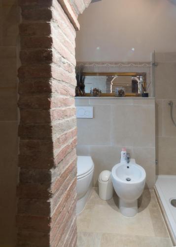 a bathroom with a brick wall and a toilet and a sink at La Casa Rossa in Coiano