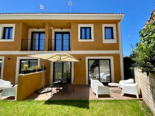 a house with a patio and an umbrella at Casas La Fuente de Saelices - Alojamiento rural in Saelices el Chico