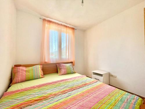 a bedroom with a bed with colorful sheets and a window at Talia Apartments in Budva