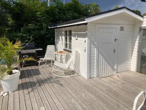 a white shed with two chairs and a table on a deck at Strandnära mysig stuga med generösa utvändiga ytor in Mellbystrand