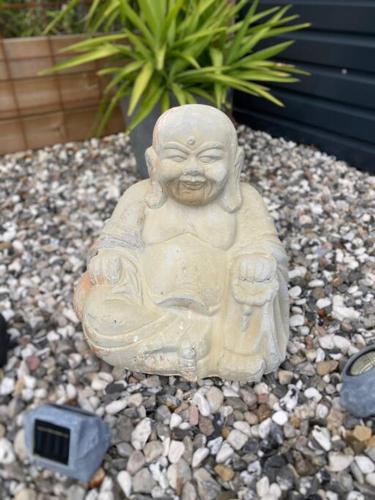 a statue of a monk sitting on a gravel at Strandnära mysig stuga med generösa utvändiga ytor in Mellbystrand