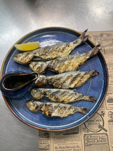 a plate of fish on a table with a lemon at Hotel AVENUE in Ravda