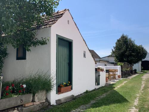 une maison blanche avec une porte verte et des fleurs dans l'établissement Kieslinghof, à Purbach am Neusiedlersee