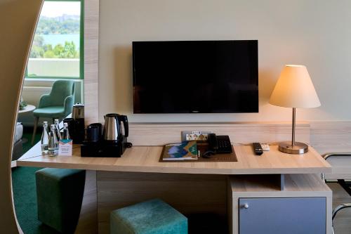 a room with a desk with a television and a lamp at Hotel Malibu in Mamaia