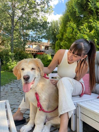 a woman sitting on a picnic table with a dog at Posada Restaurante Fuenteplateada in Collado Hermoso