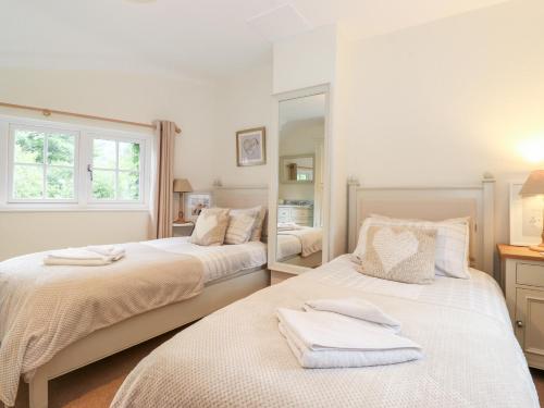 a bedroom with two beds and a mirror at Holly Cottage in Ambleside