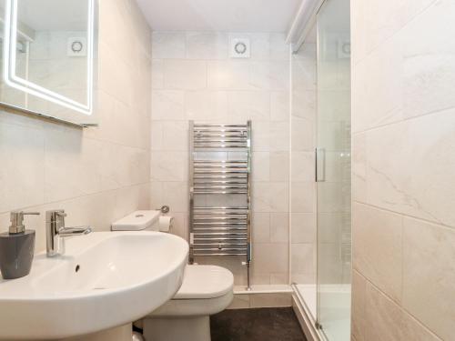 a white bathroom with a toilet and a sink at Holly Cottage in Ambleside