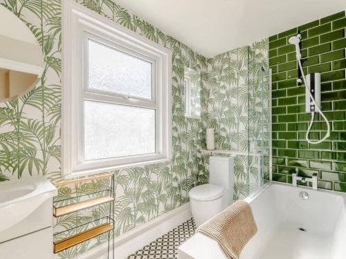 ein Bad mit grünen Fliesen, einer Badewanne und einem Fenster in der Unterkunft Walpole FRONT House sleeps 13-15 in Margate