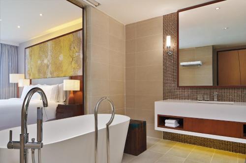 a bathroom with a tub and a bed and a mirror at The Westin Desaru Coast Resort in Desaru