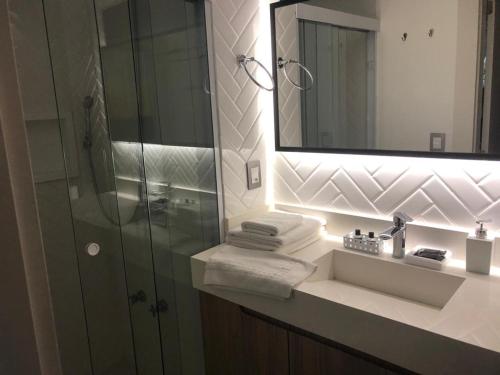 W łazience znajduje się umywalka, lustro i prysznic. w obiekcie Apart-hotel Central com Spa w mieście Balneário Camboriú